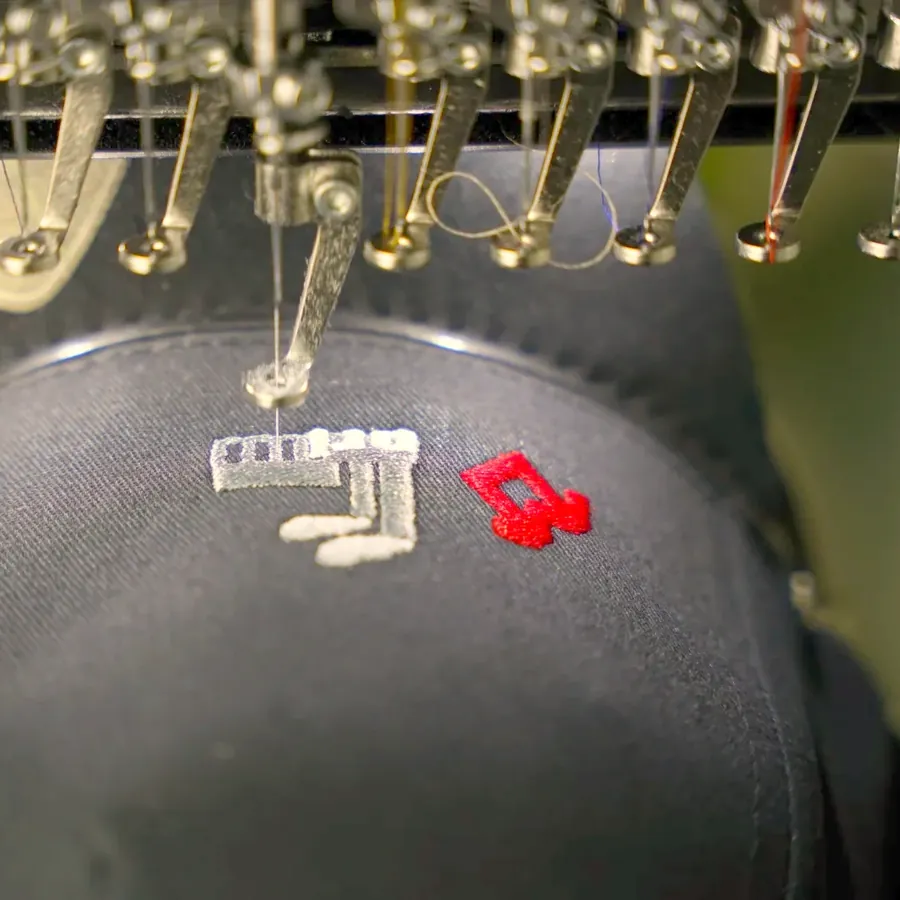 Stickkopf mit fünfzehn Nadeln setzt weisses und rotes Garn auf eine dunkle Cap