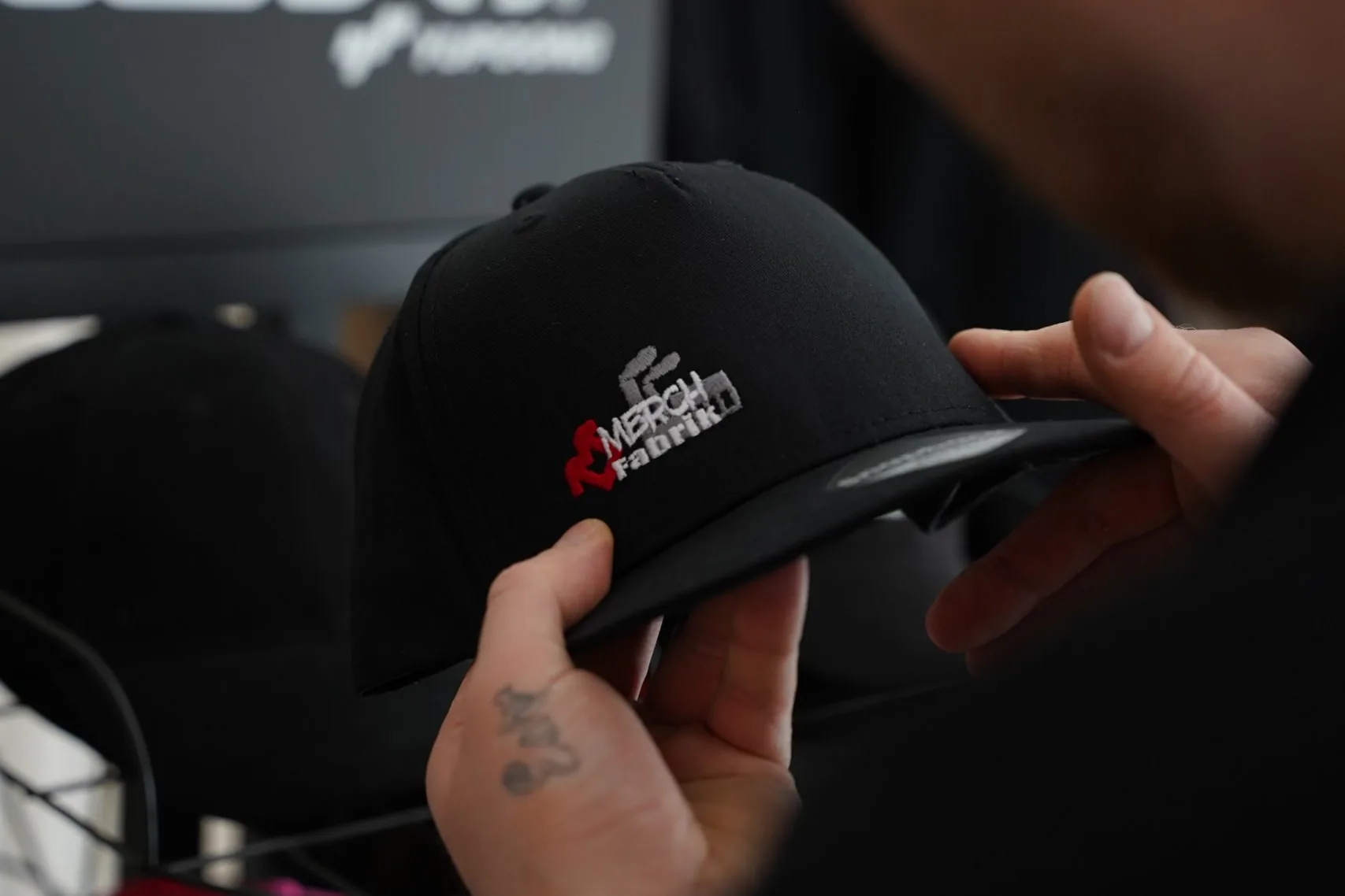 Bestickte Cap wird in der Werkstatt in der Hand geprüft