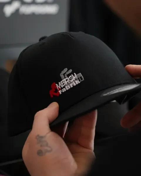 Bestickte Cap wird in der Werkstatt in der Hand geprüft