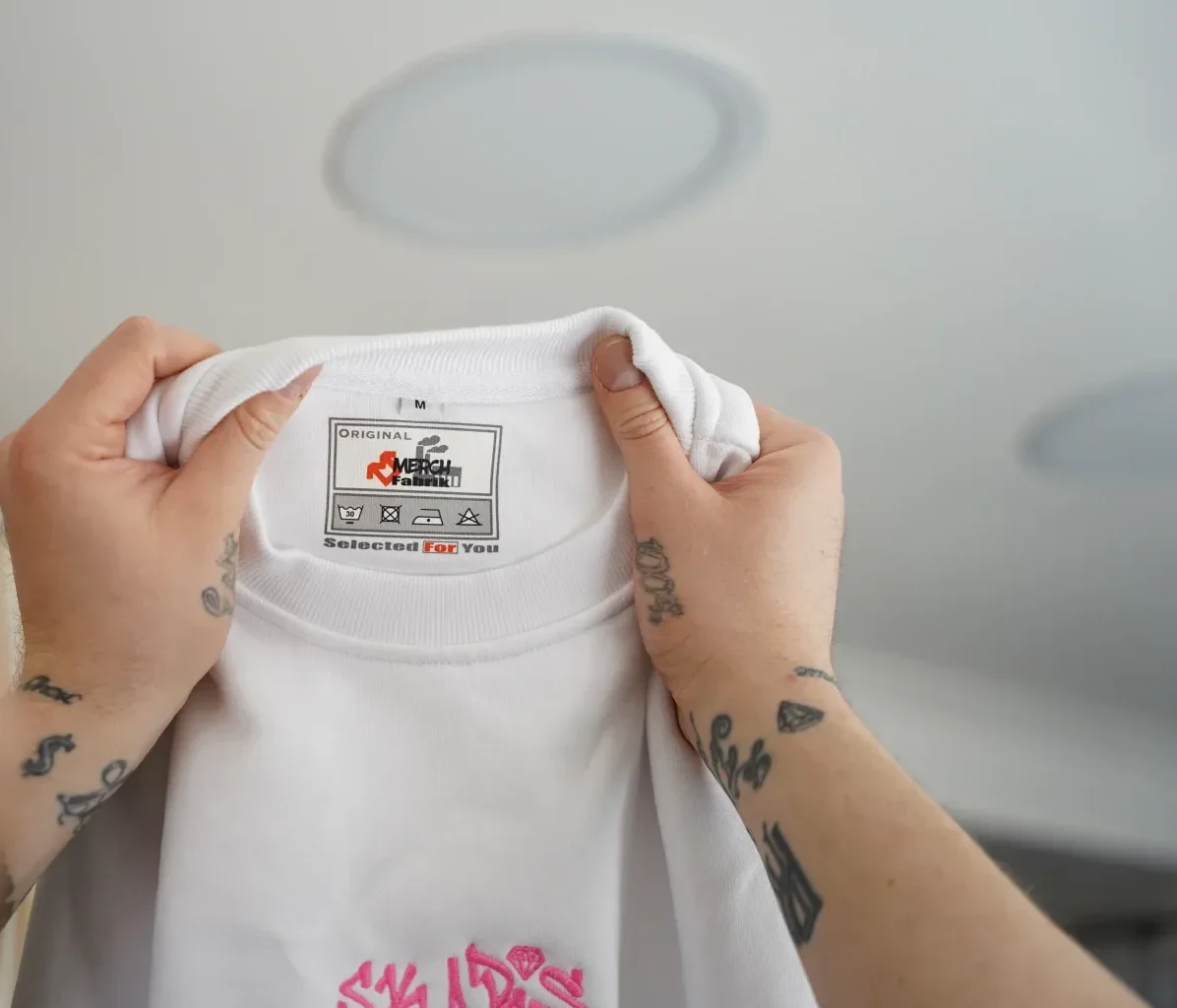 Fertig veredeltes Shirt mit Streetwear-Motiv wird in der Werkstatt hochgehalten